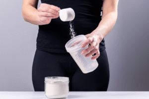 Mujer sirviendo un scoop de creatina antes de entrenar.